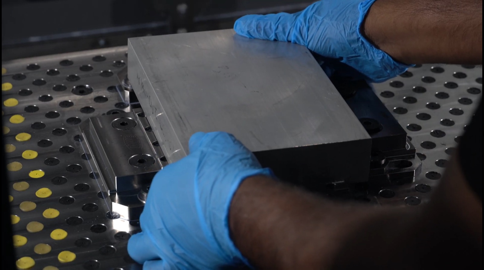 Machinist clamping an aluminium workpiece during CNC machine setup