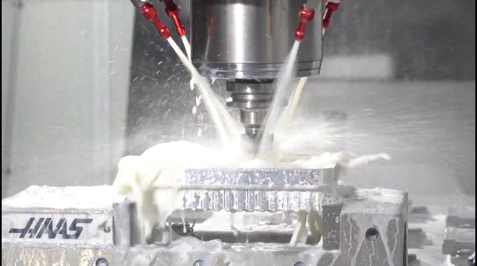 HAAS VF-2 CNC machine cutting a custom aluminium component with coolant